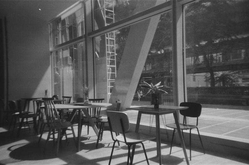 portrait of a seated person taken through the window from within the interior of a cafe
